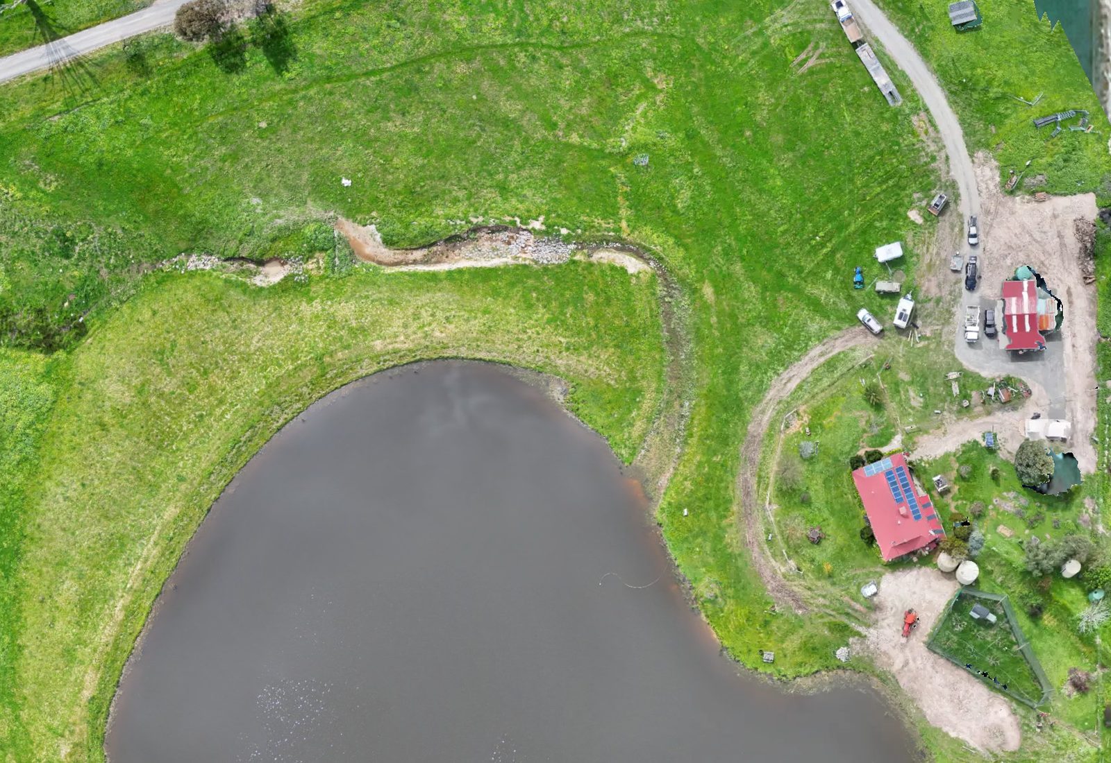 Stoney Creek Farm from the air, showing green paddocks, a large dam, tracks, sheds and houses with red roofs, Skyhawk Aerial drone imagery